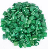 Multiple tiny green emerald gemstones arranged in a centered circular layout, creating a neat and symmetrical pattern on a plain background.